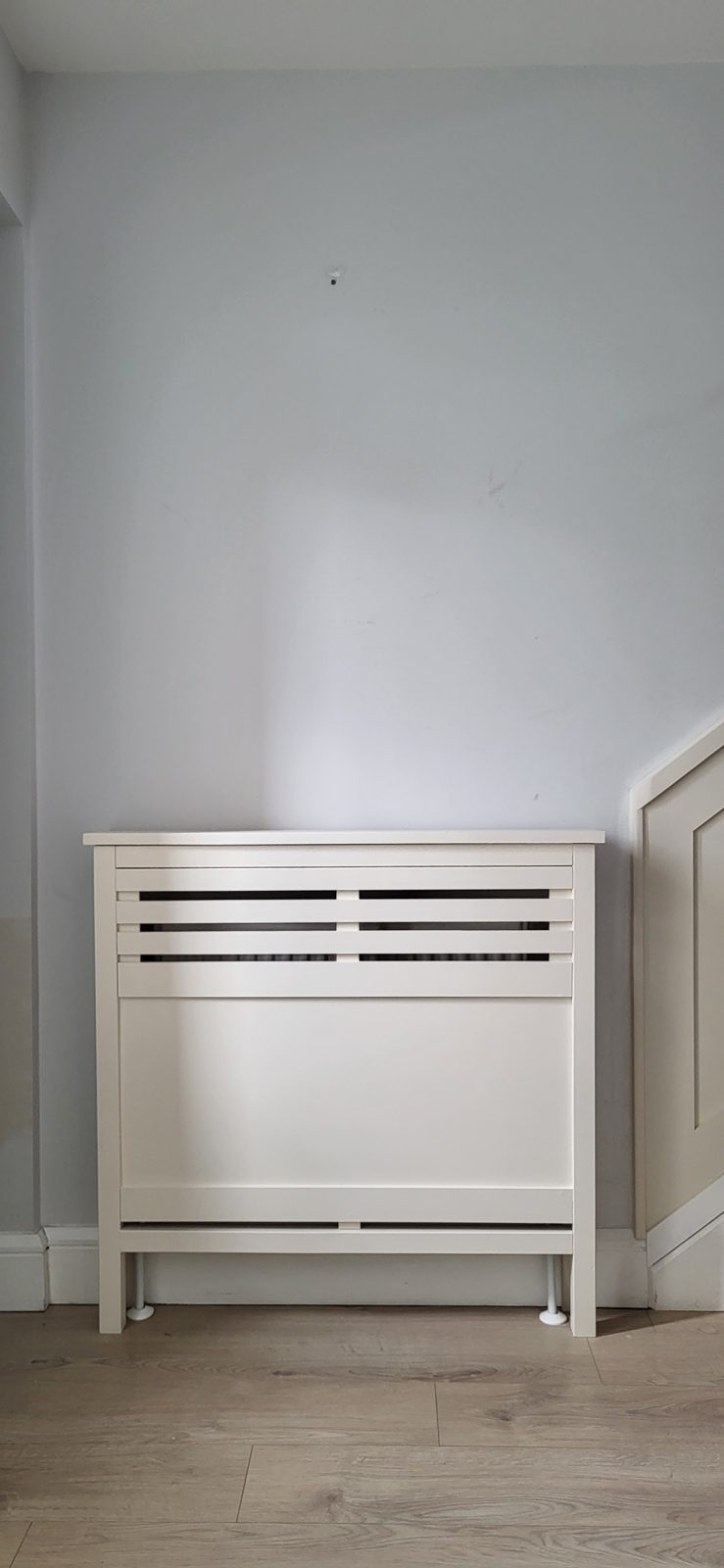 A white radiator cover fitted in a hallway